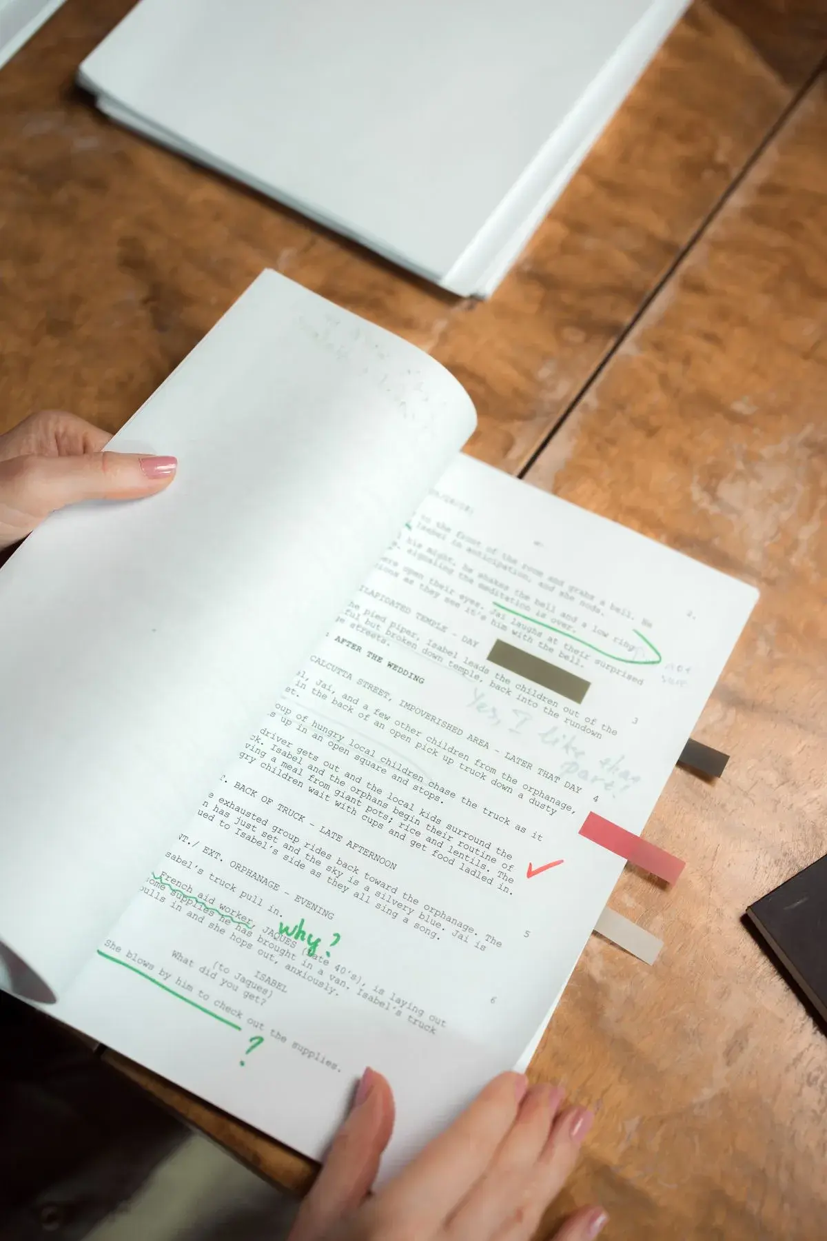 Des mains relisent des pages de manuscrit annotées à la main.